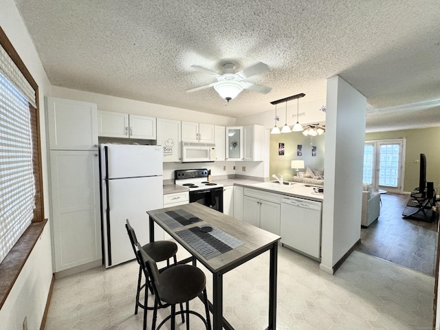 kitchen with light countertops, white cabinets, a sink, ceiling fan, and white appliances