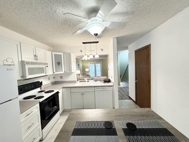 kitchen featuring light countertops, a ceiling fan, white cabinetry, a sink, and white appliances