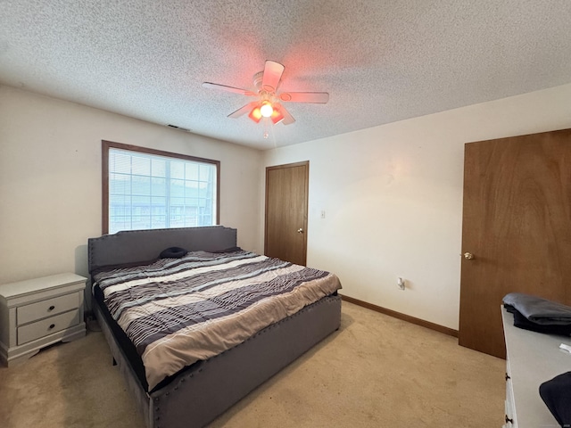 bedroom with visible vents, light colored carpet, ceiling fan, a textured ceiling, and baseboards