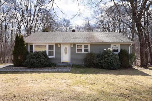 ranch-style home featuring roof with shingles and a front lawn