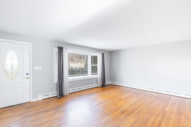 foyer featuring a baseboard heating unit and wood finished floors