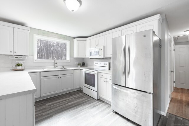 kitchen with light wood-type flooring, white appliances, white cabinets, and a sink