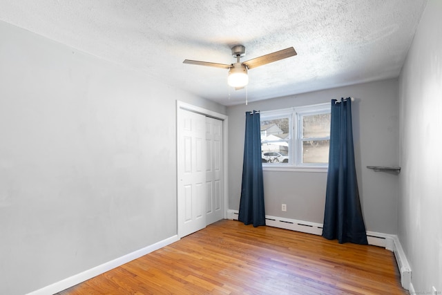 unfurnished bedroom featuring a closet, light wood-style floors, ceiling fan, a textured ceiling, and baseboards