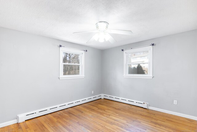 empty room featuring a wealth of natural light, baseboards, and wood finished floors