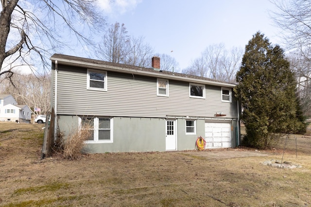 rear view of property featuring a garage and a chimney