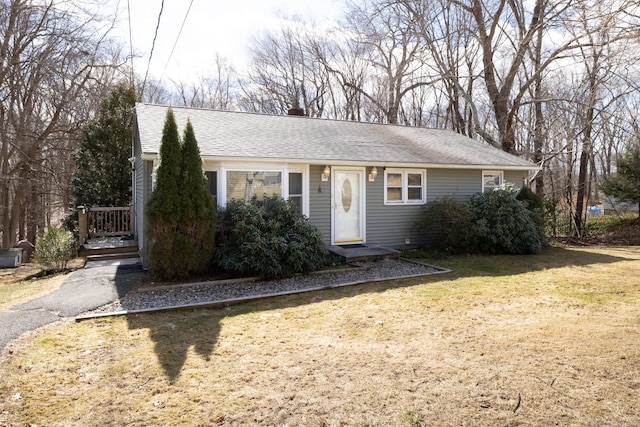 view of front of house featuring a chimney, roof with shingles, and a front yard