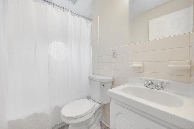 full bath with curtained shower, tile walls, toilet, and vanity