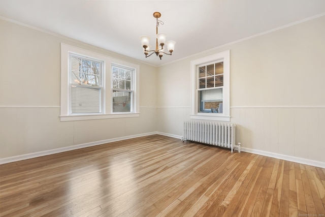 unfurnished room with a chandelier, wainscoting, hardwood / wood-style floors, and radiator heating unit