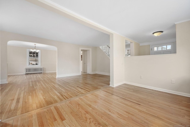 interior space with wood finished floors, baseboards, stairs, radiator, and an inviting chandelier