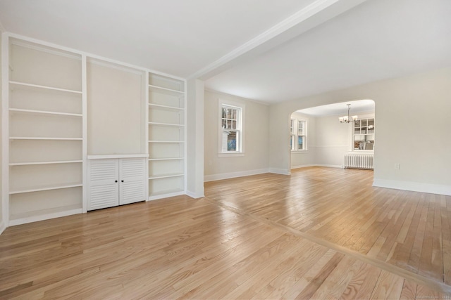 unfurnished living room with arched walkways, light wood-style flooring, a notable chandelier, baseboards, and radiator