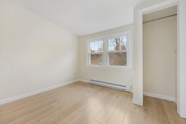 unfurnished bedroom with a baseboard heating unit, light wood-type flooring, and baseboards