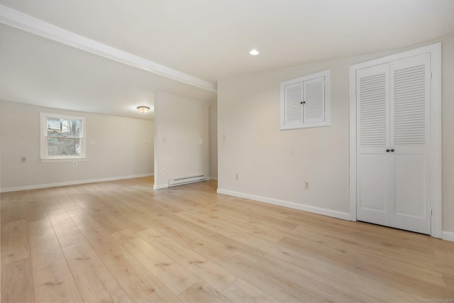 interior space featuring a baseboard heating unit, light wood-type flooring, and baseboards