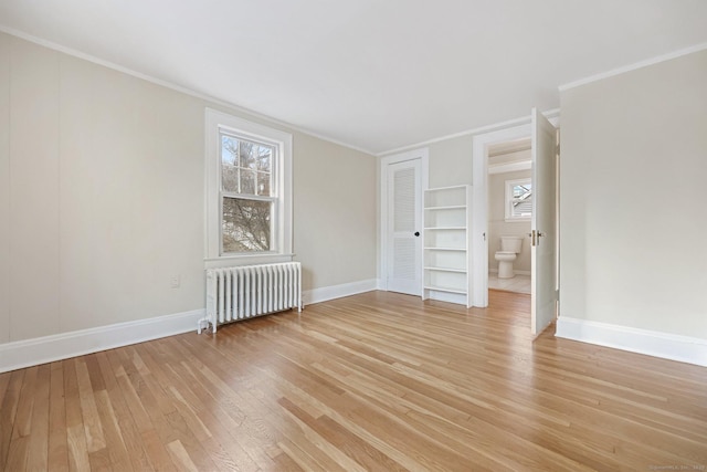 unfurnished room with ornamental molding, light wood-type flooring, a wealth of natural light, and radiator