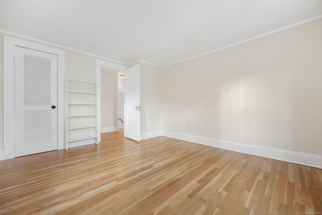 unfurnished bedroom with light wood-style floors, a closet, ornamental molding, and baseboards