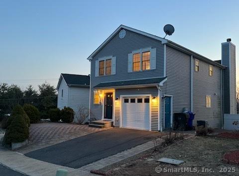 view of front of house featuring aphalt driveway, a chimney, and an attached garage