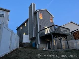 back of house featuring a deck, a chimney, and fence