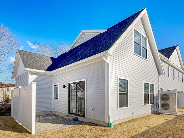 rear view of house with ac unit, roof with shingles, a patio, and fence