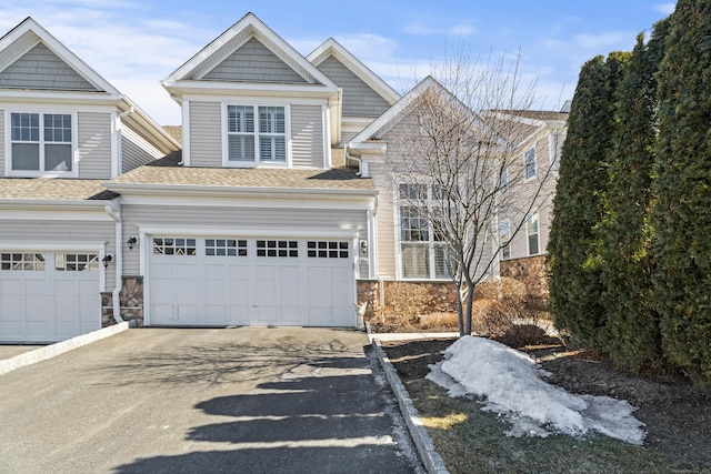 view of front of home featuring a garage, stone siding, a shingled roof, and aphalt driveway