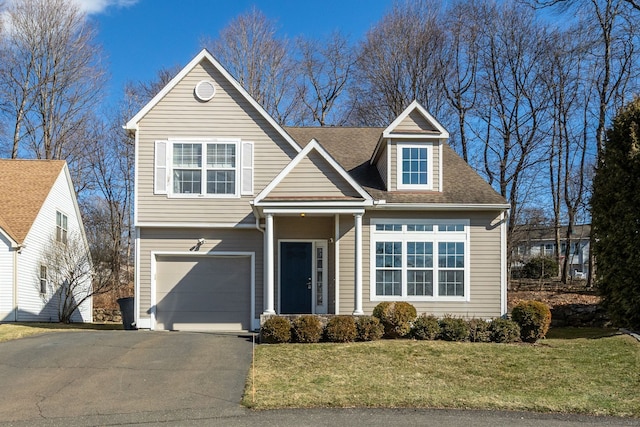 traditional-style home featuring driveway, an attached garage, a front lawn, and a shingled roof