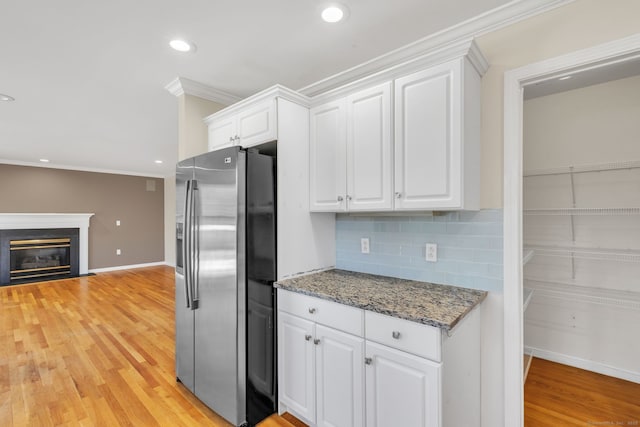 kitchen featuring light wood finished floors, tasteful backsplash, white cabinets, ornamental molding, and stainless steel refrigerator with ice dispenser