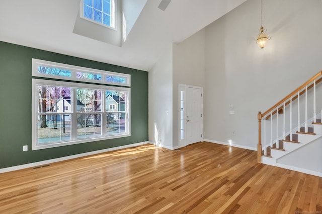 foyer with visible vents, stairway, wood finished floors, high vaulted ceiling, and baseboards