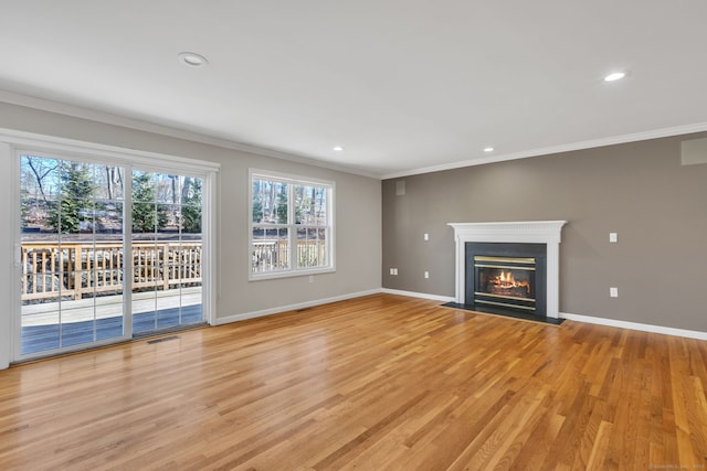 unfurnished living room featuring ornamental molding, a glass covered fireplace, visible vents, and baseboards