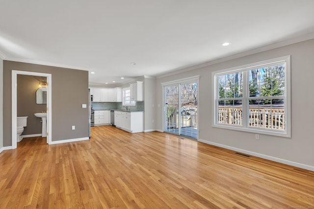 unfurnished living room with light wood finished floors, baseboards, and crown molding