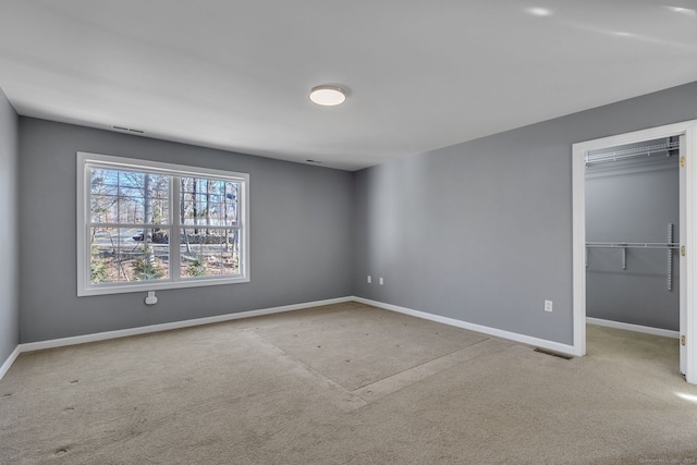 unfurnished bedroom with carpet floors, visible vents, baseboards, a closet, and a walk in closet