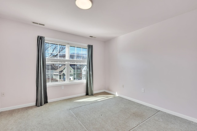 empty room with carpet flooring, visible vents, and baseboards