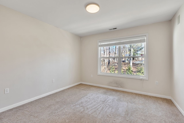 carpeted empty room featuring baseboards and visible vents