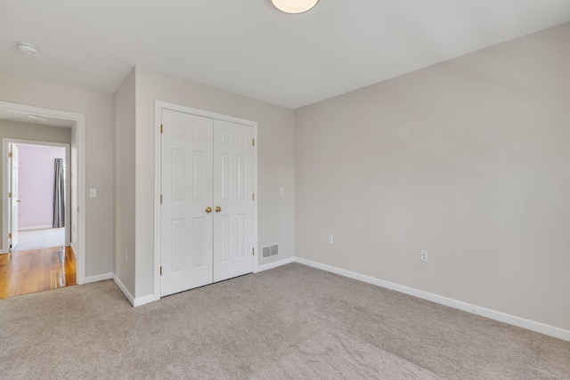 unfurnished bedroom with visible vents, a closet, baseboards, and carpet flooring