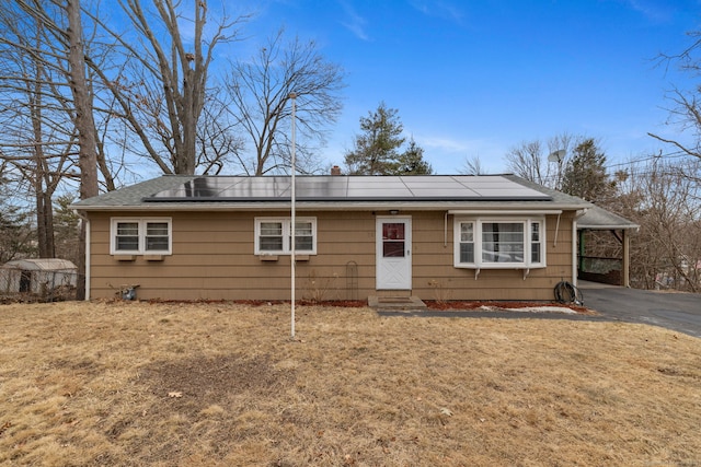 view of front of property featuring a front yard, roof mounted solar panels, driveway, and entry steps