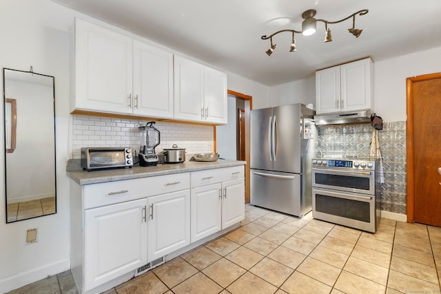 kitchen featuring a toaster, stainless steel appliances, decorative backsplash, white cabinetry, and under cabinet range hood