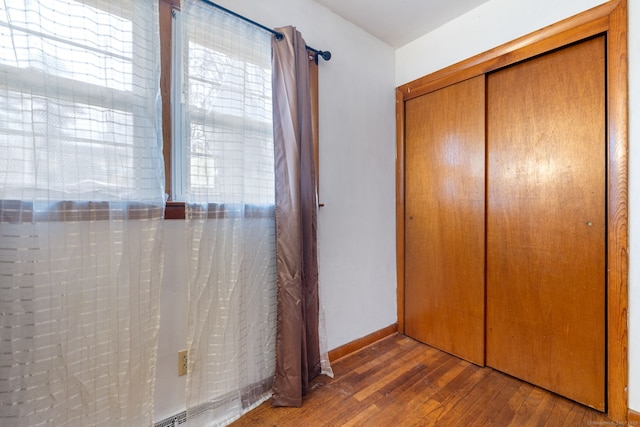 unfurnished bedroom with a closet, baseboards, and hardwood / wood-style floors