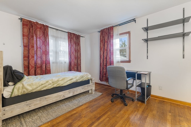 bedroom with wood-type flooring and baseboards