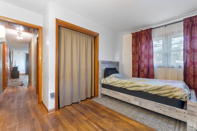 bedroom featuring attic access, baseboards, and hardwood / wood-style floors