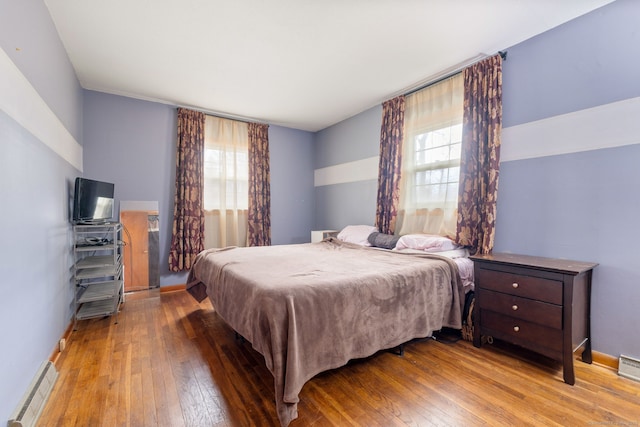 bedroom featuring baseboard heating, hardwood / wood-style flooring, and baseboards