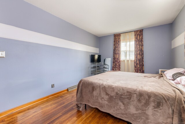 bedroom with visible vents, baseboards, and wood finished floors