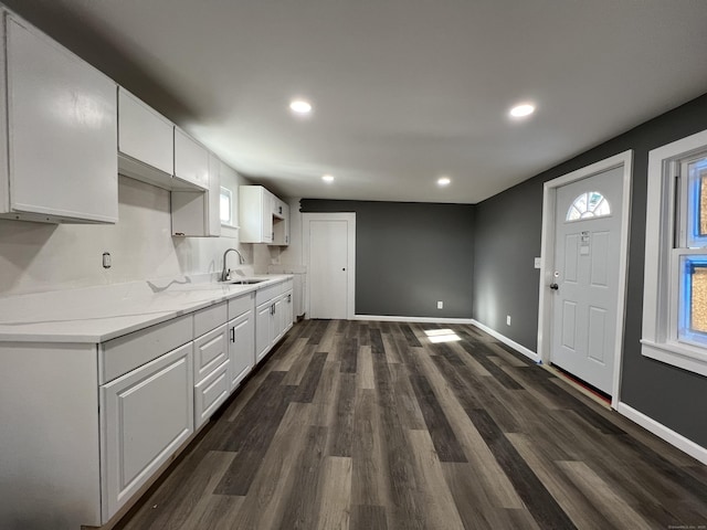 kitchen featuring baseboards, dark wood-style flooring, white cabinetry, a sink, and recessed lighting