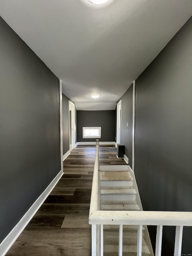 hallway with dark wood-type flooring and baseboards