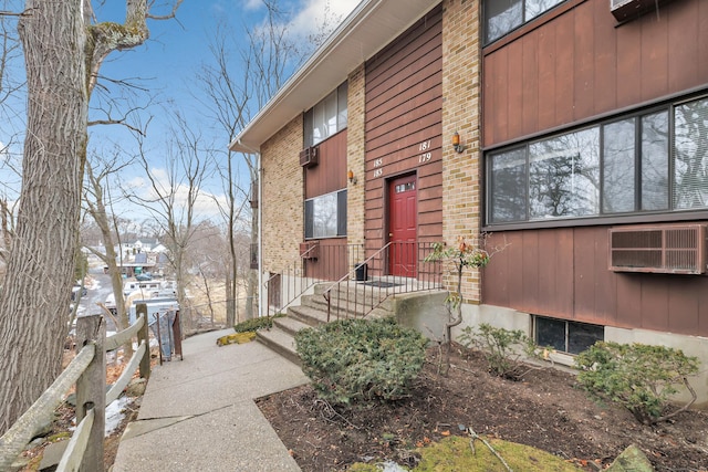 property entrance featuring fence and brick siding