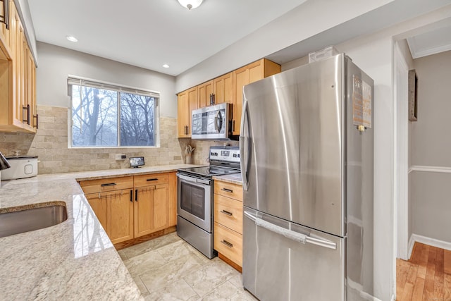 kitchen featuring stainless steel appliances, a sink, light stone counters, and tasteful backsplash