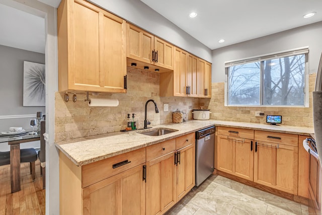 kitchen with light stone counters, decorative backsplash, light brown cabinets, a sink, and dishwasher