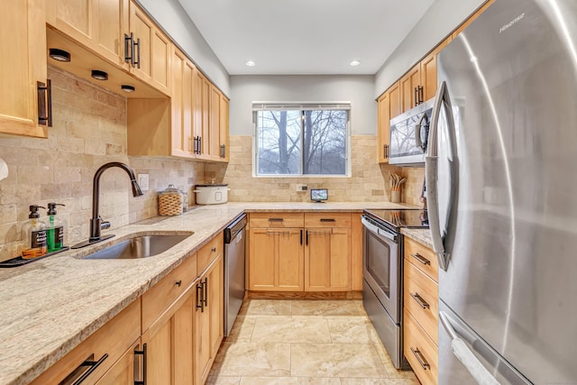 kitchen featuring decorative backsplash, light stone counters, stainless steel appliances, a sink, and recessed lighting