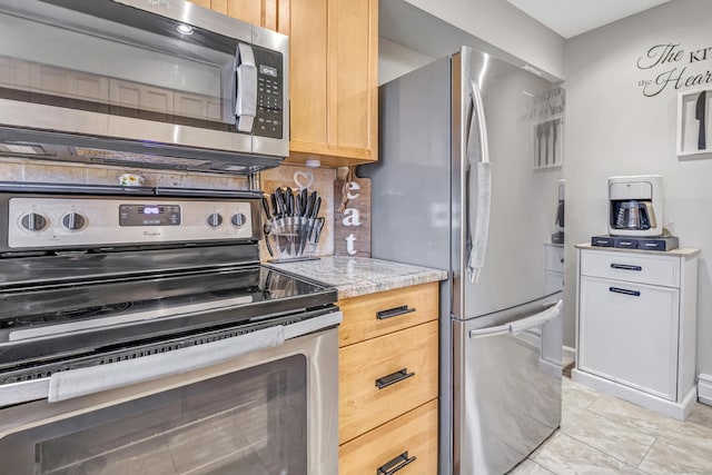 kitchen featuring light stone counters, stainless steel appliances, decorative backsplash, and light brown cabinetry