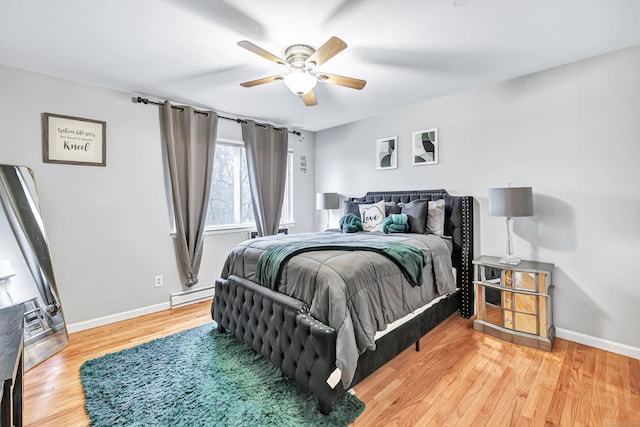 bedroom with a baseboard radiator, ceiling fan, baseboards, and wood finished floors