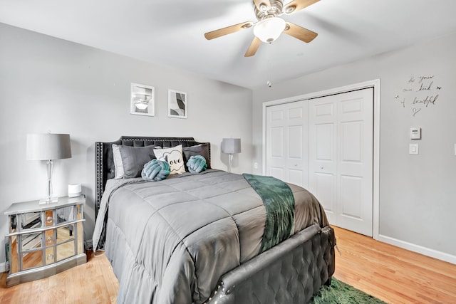 bedroom featuring ceiling fan, a closet, wood finished floors, and baseboards