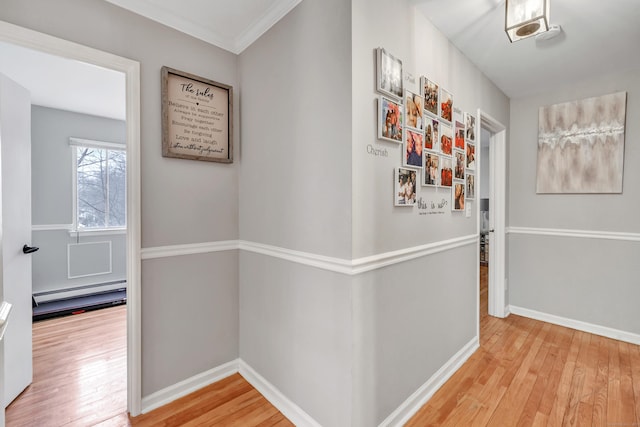 corridor featuring a baseboard heating unit, wood-type flooring, crown molding, and baseboards