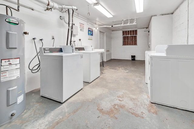 laundry area with water heater, washing machine and clothes dryer, and concrete block wall