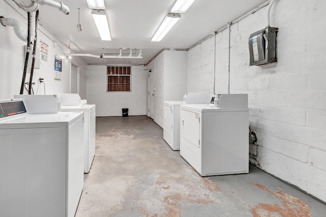 community laundry room featuring washing machine and dryer and concrete block wall